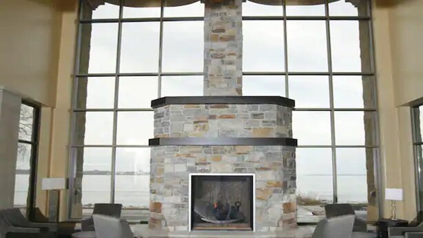 A stone fireplace with a glass enclosure, large windows, and a view of the outdoors. - Doubletree by Hilton Bemidji (Bemidji)
