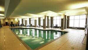 An indoor swimming pool with multiple lanes, chairs around the pool, and large windows providing natural light. - Doubletree by Hilton Bemidji (Bemidji)