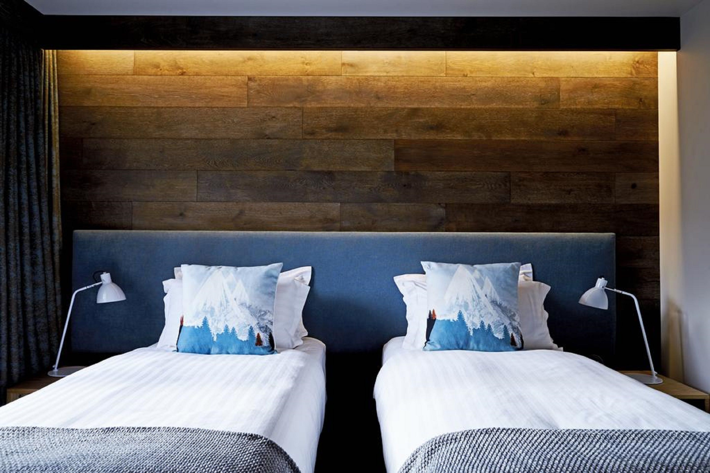 Una habitación de hotel con dos camas, un cabecero de madera y una mesita de noche con lámpara.