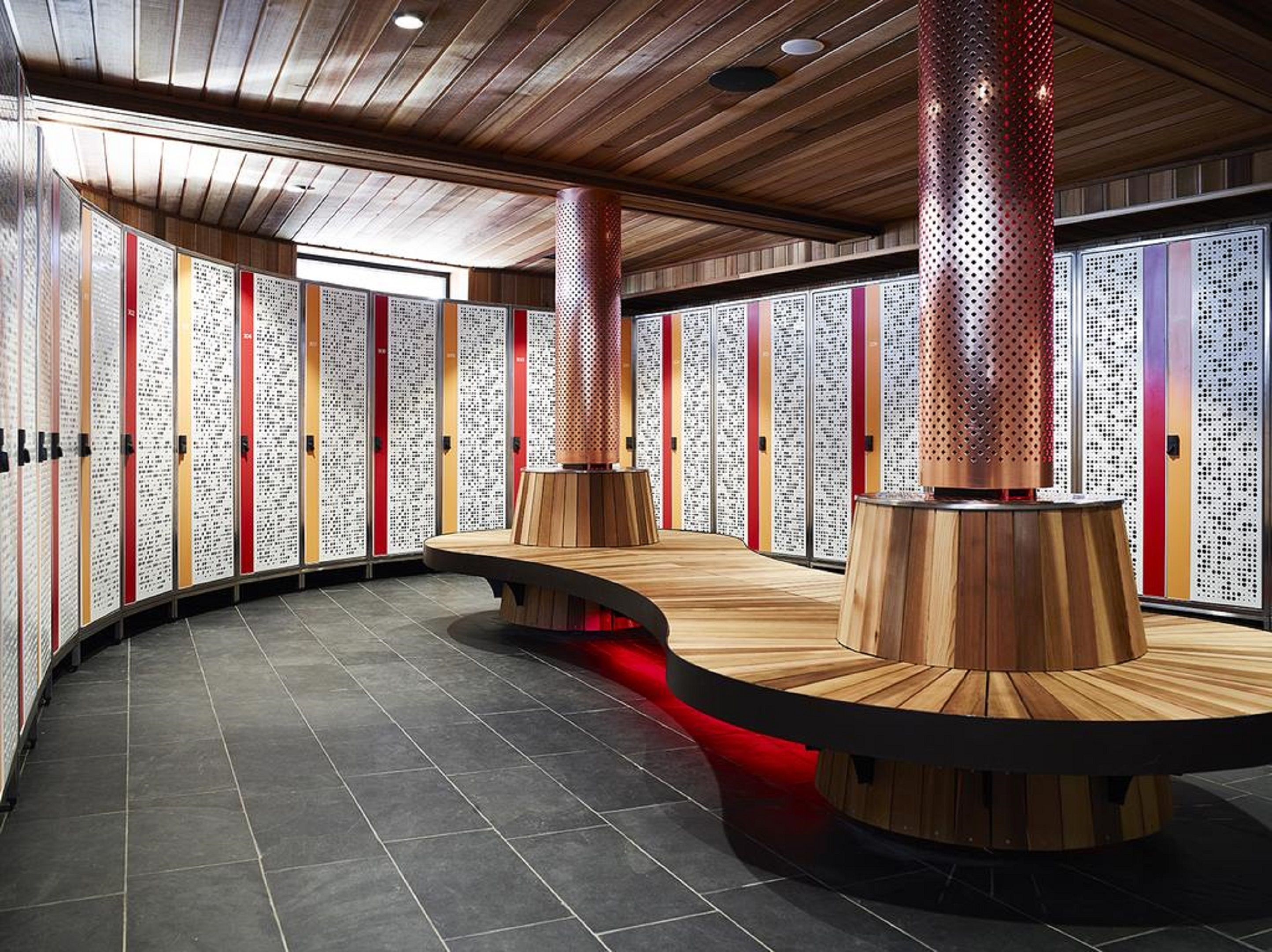 A modern interior with wooden panel walls, a curved seating area, and a central column with perforated design.