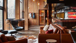 A modern lounge area with leather sofas, a bar with a red-lit counter, and wooden walls. - Astra Falls Creek (Falls Creek)