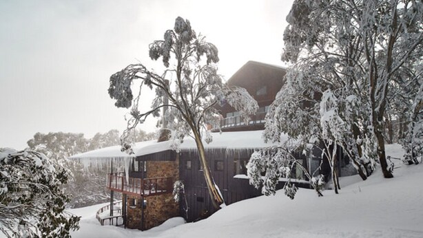 A snow-covered landscape with a rustic building, trees, and a clear sky. - Astra Falls Creek (Falls Creek)