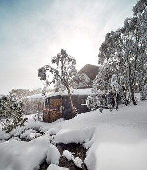 A snow-covered landscape with a rustic building, trees, and a clear sky. - Astra Falls Creek (Falls Creek)