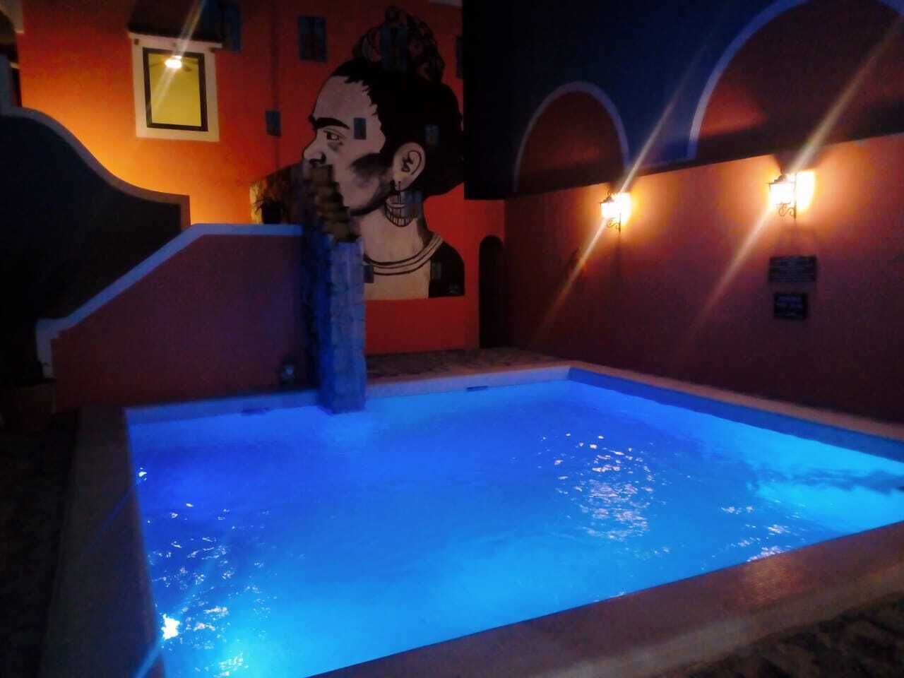 A pool with blue lighting, a mural on the wall, and wall-mounted lights.