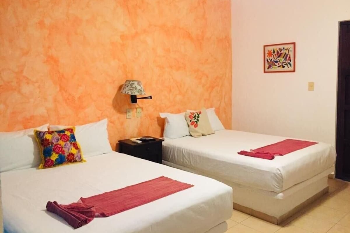 Ein Hotelzimmer mit zwei Betten, einem Nachttisch, einer Lampe und einem Bild an der Wand.