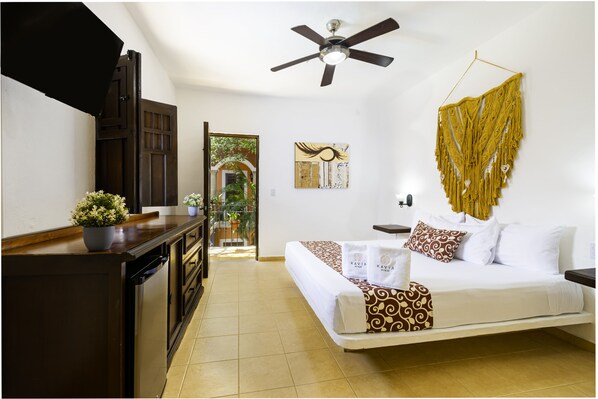 A hotel room with a bed, a ceiling fan, a wall-mounted macrame piece, and a view of the outdoors. - Hotel Casa De Las Flores (Playa del Carmen)