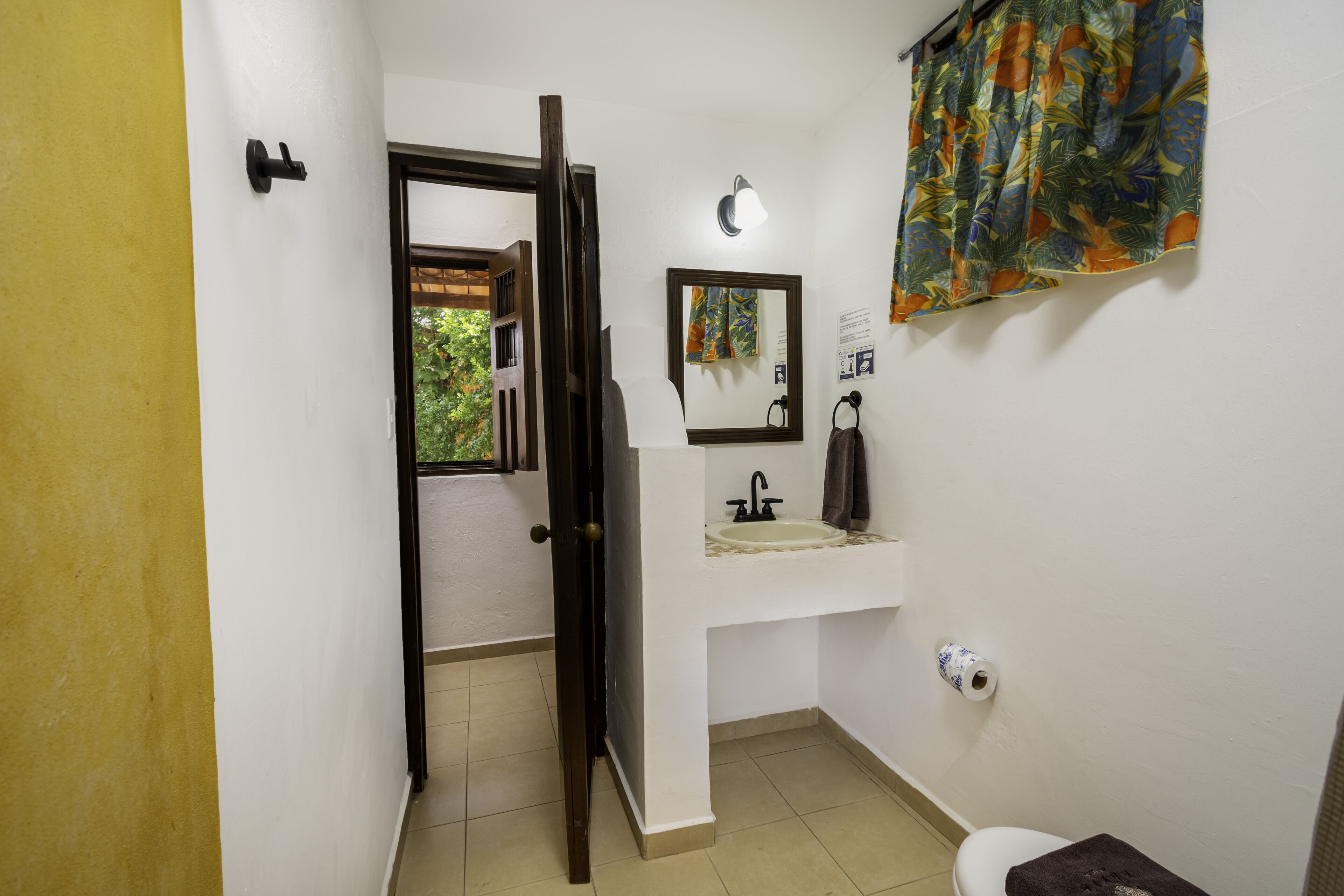 Une salle de bain avec un lavabo blanc, un miroir, des toilettes et un rideau de douche.