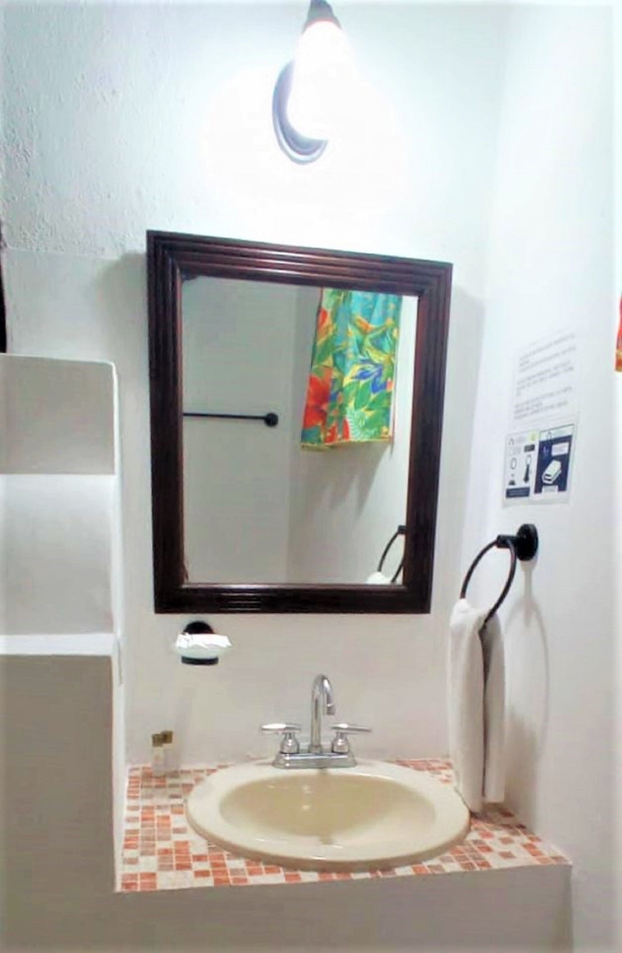 Un baño con un lavabo blanco, un espejo y un perchero para toallas.