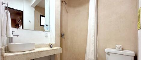A bathroom with a white sink, mirror, shower, and toilet.
