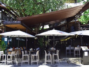 An outdoor cafe with tables and chairs under shaded umbrellas.