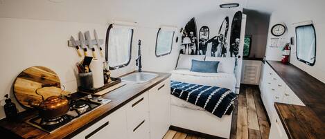 A compact kitchen with a stove, sink, and wooden countertop.