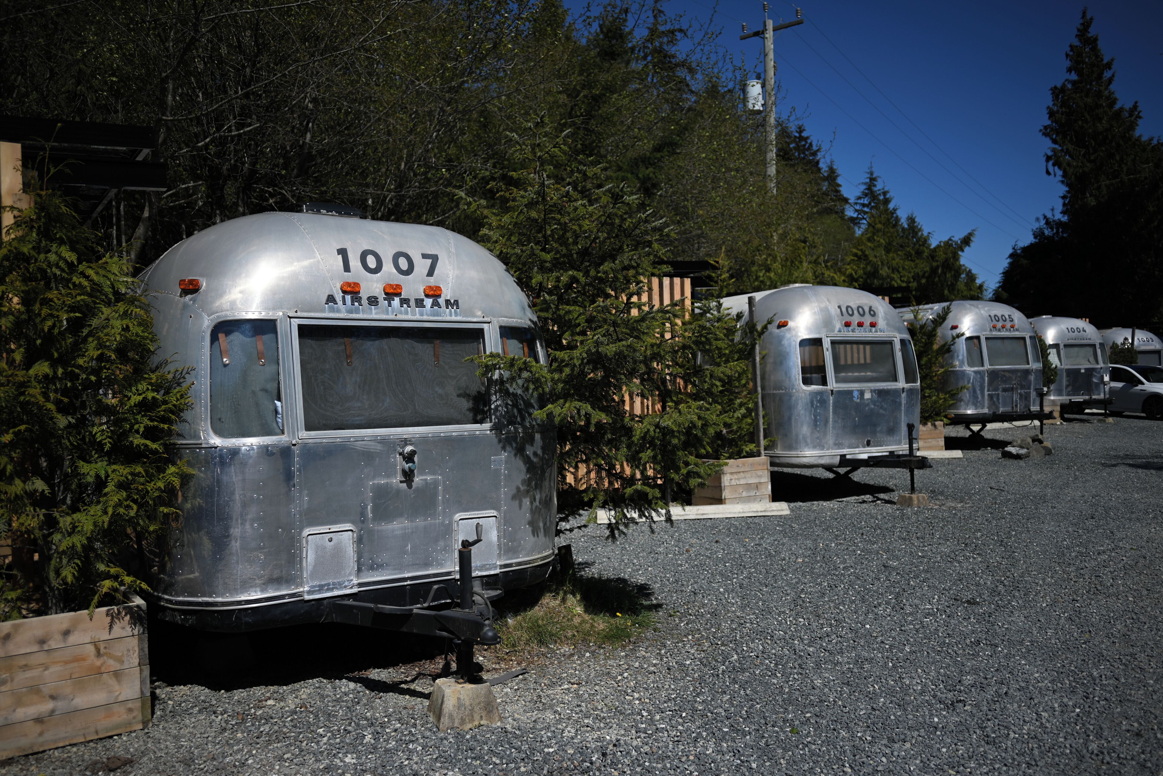 Des caravanes anciennes sont garées sur un sol recouvert de gravier, chacune portant un numéro visible et le mot « AIRSTREAM » sur le côté.
