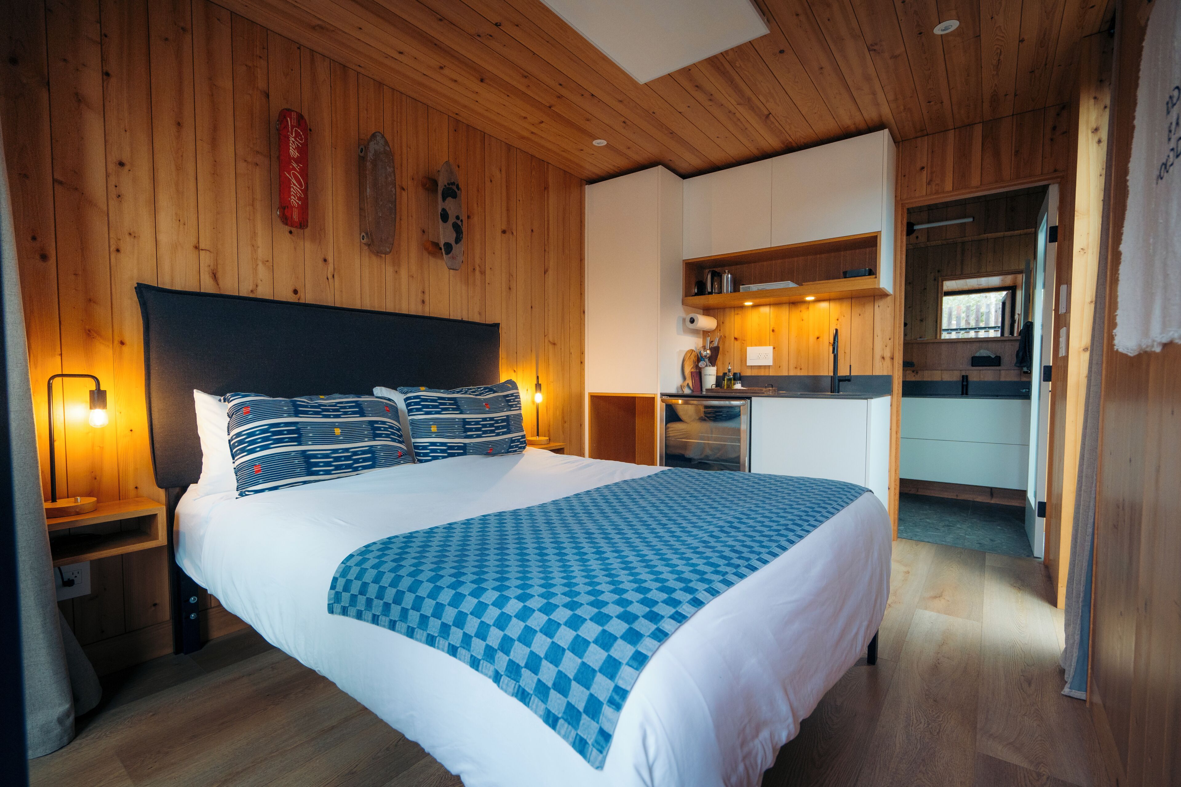 Een slaapkamer met een groot bed, houten wanden, een kitchenette en een badkamer.