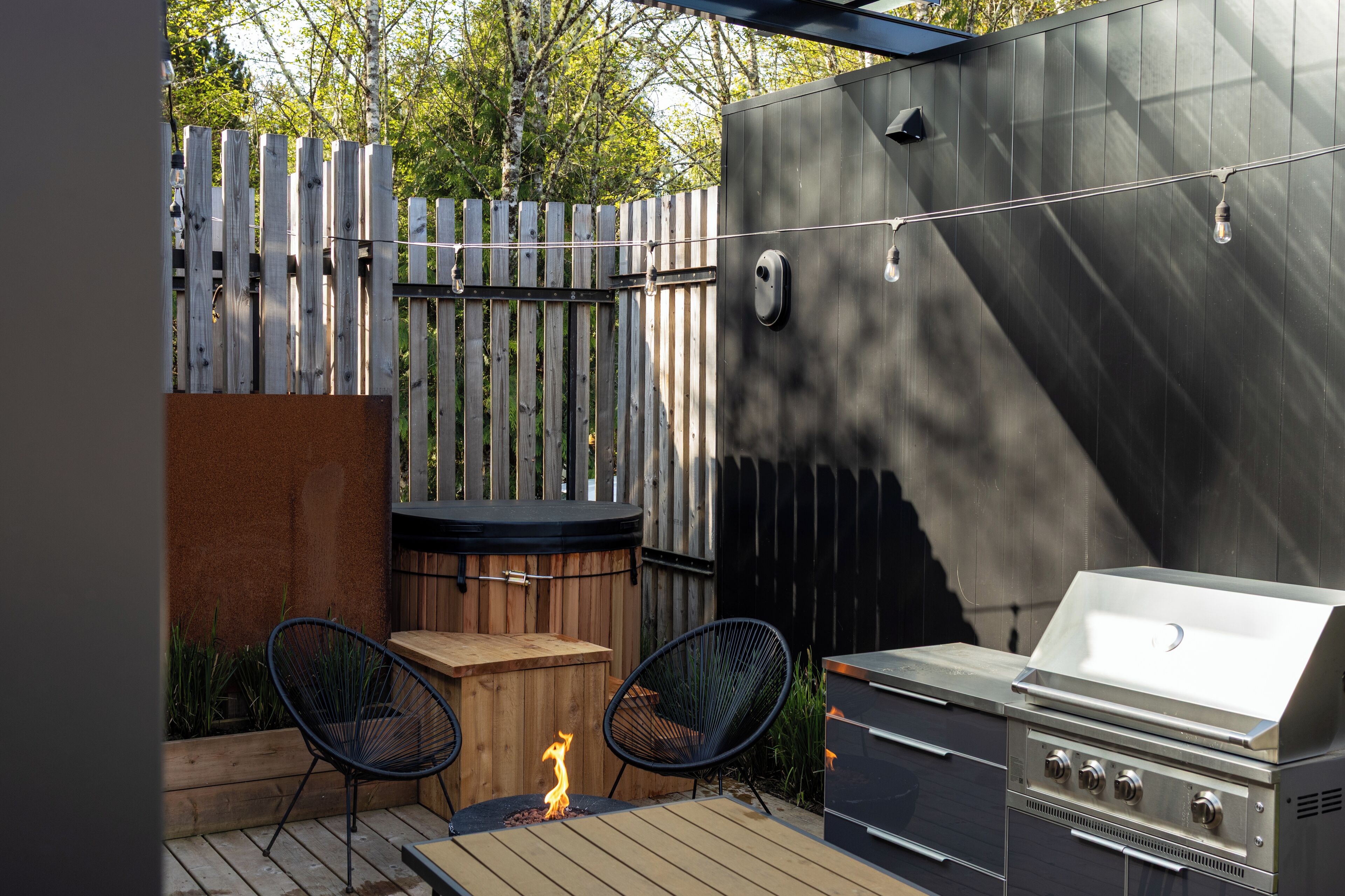 Eine Terrasse im Freien mit Grill, zwei Stühlen und einem Holztisch.