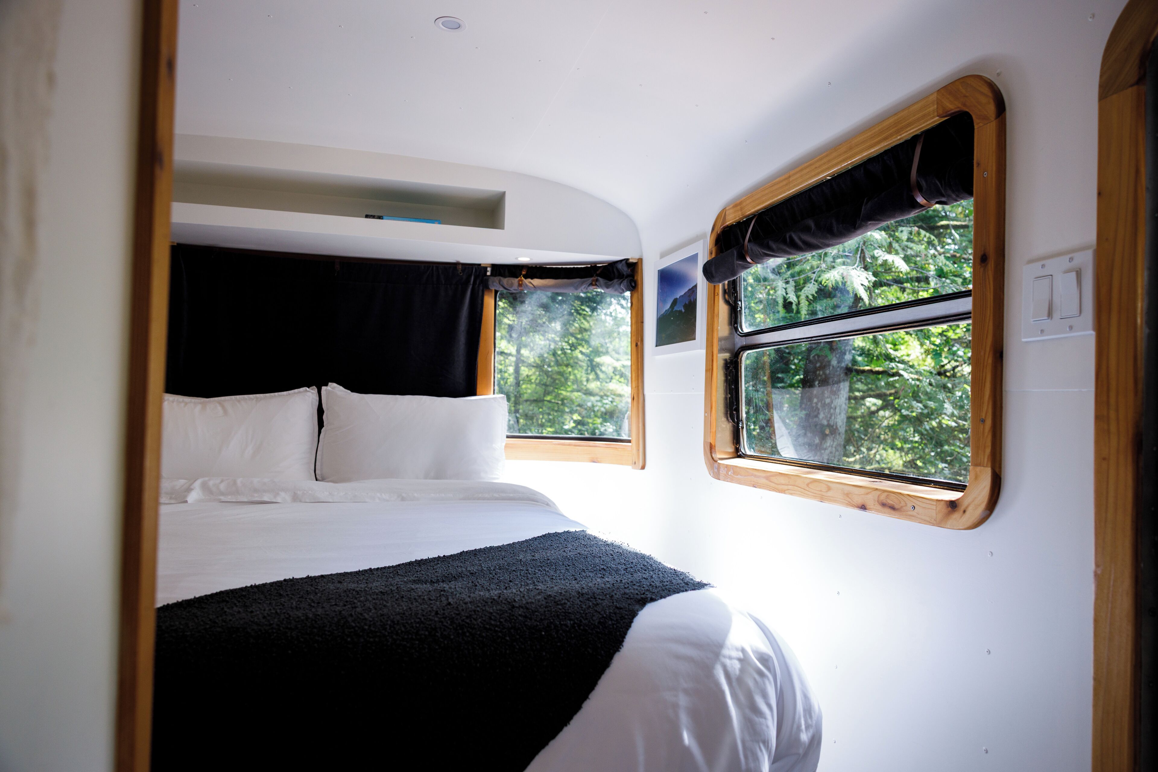 A bedroom with a bed, a window, and a wall-mounted light fixture.