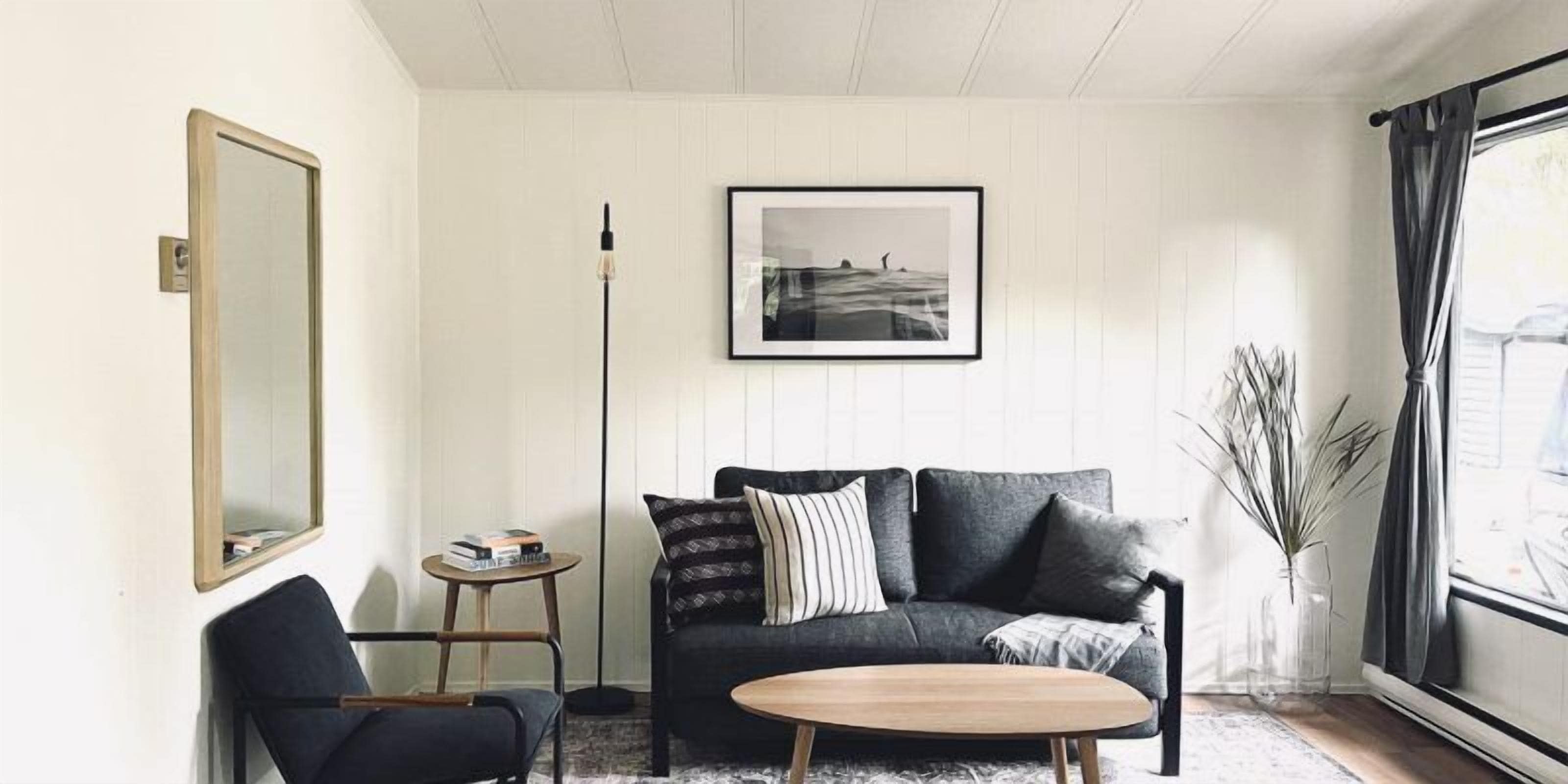Een woonkamer met een bank, een salontafel, een stoel, een vloerlamp en een ingelijste foto aan de muur.