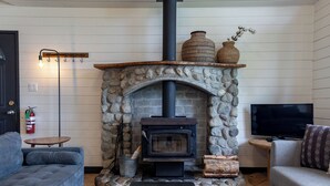 A cozy living room with a stone fireplace, a television, and two sofas. - Mackenzie Beach Resort (Tofino)