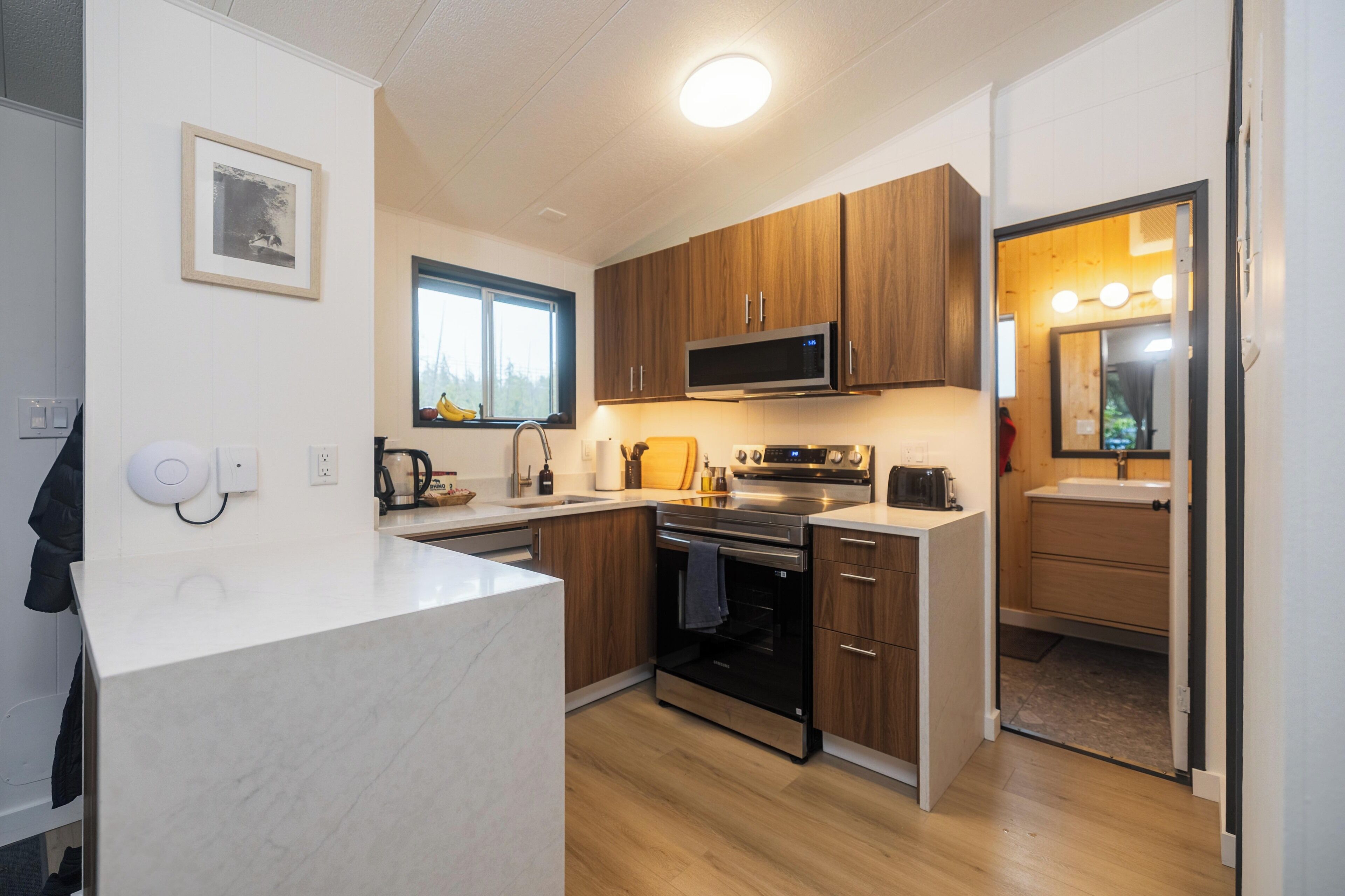 A compact kitchen with wooden cabinets, a built-in microwave, and a stainless steel oven.