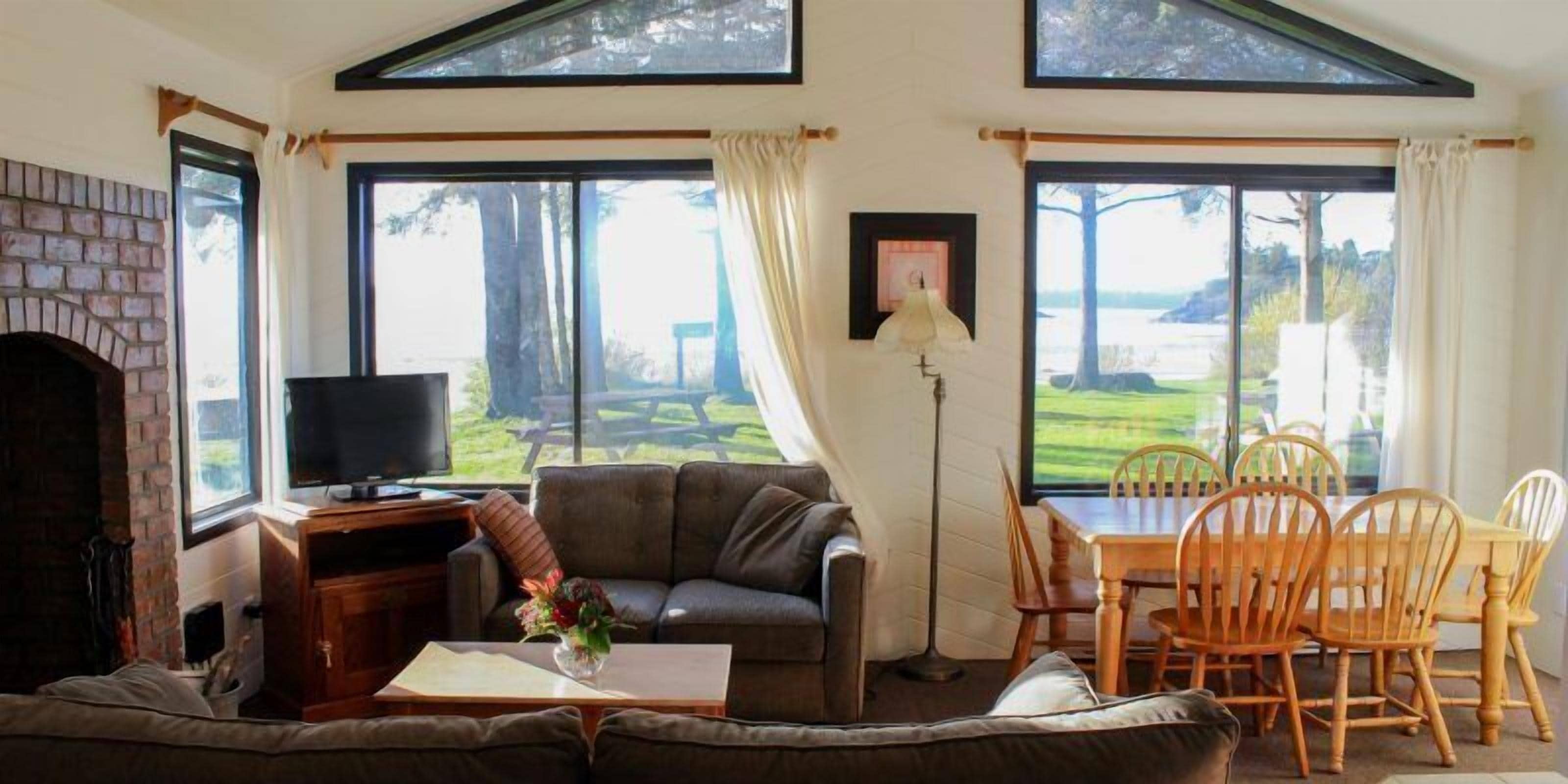 A living room with a fireplace, a sofa, a television, and a dining area with chairs and a table.