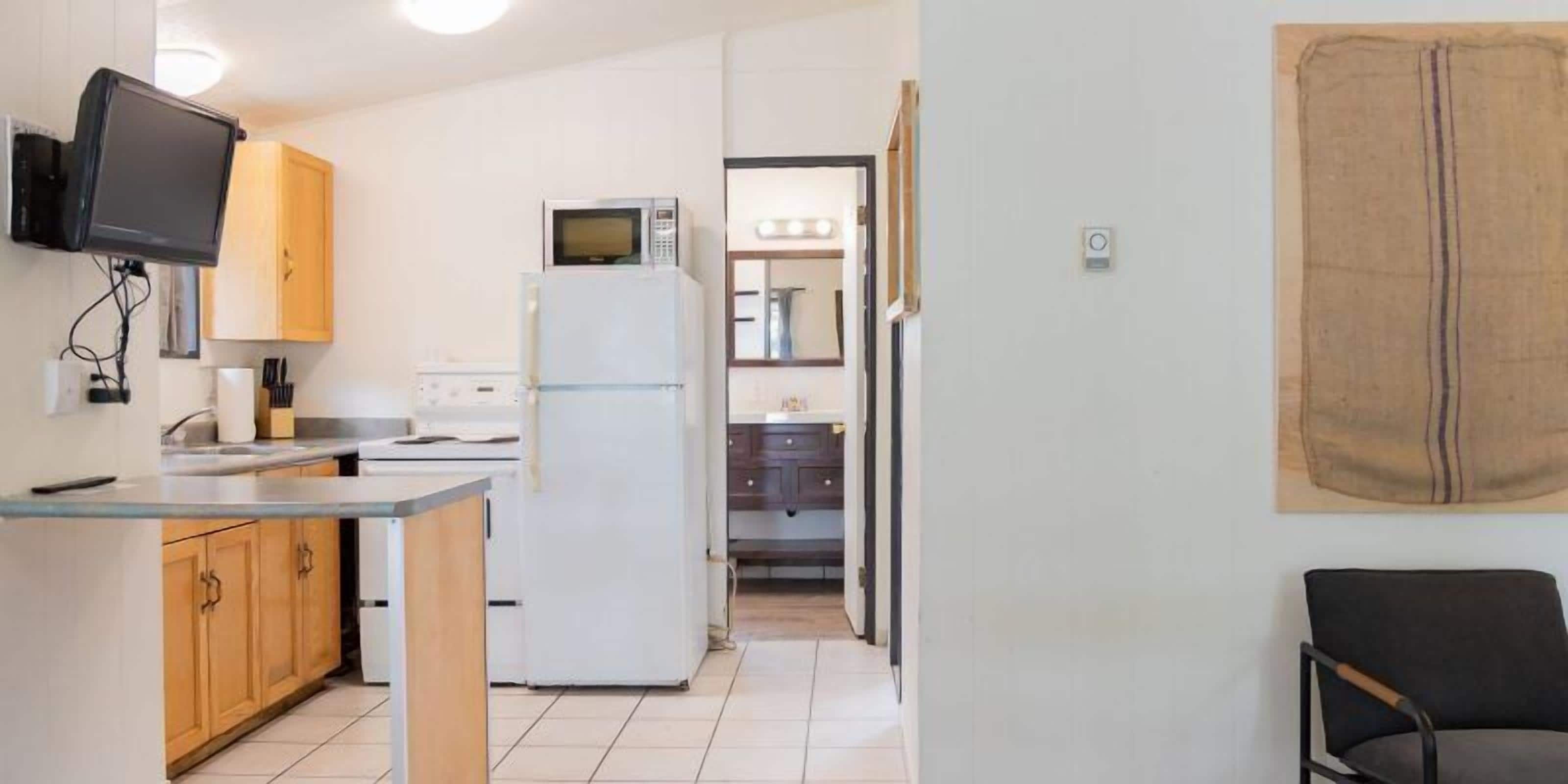 A compact kitchen with a refrigerator, microwave, and wooden cabinets.