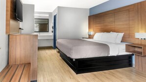 A modern hotel room with a large bed, a flat-screen TV mounted on the wall, and a wooden headboard. - Quality Inn Madison - Huntsville (Madison)