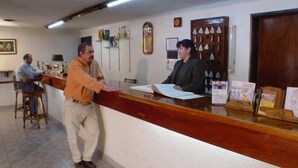 A reception area with a wooden counter, a clock, and a display of keys. - Hotel América (Mendoza)