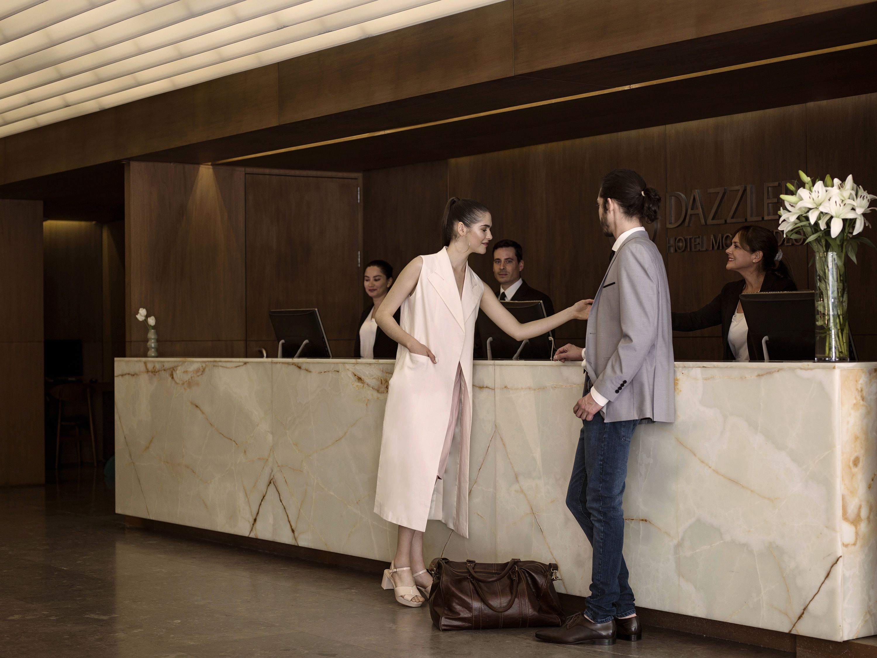 A hotel reception area with marble counters, a reception desk, and a sign that reads "DAZZLE HOTEL MEXICO".