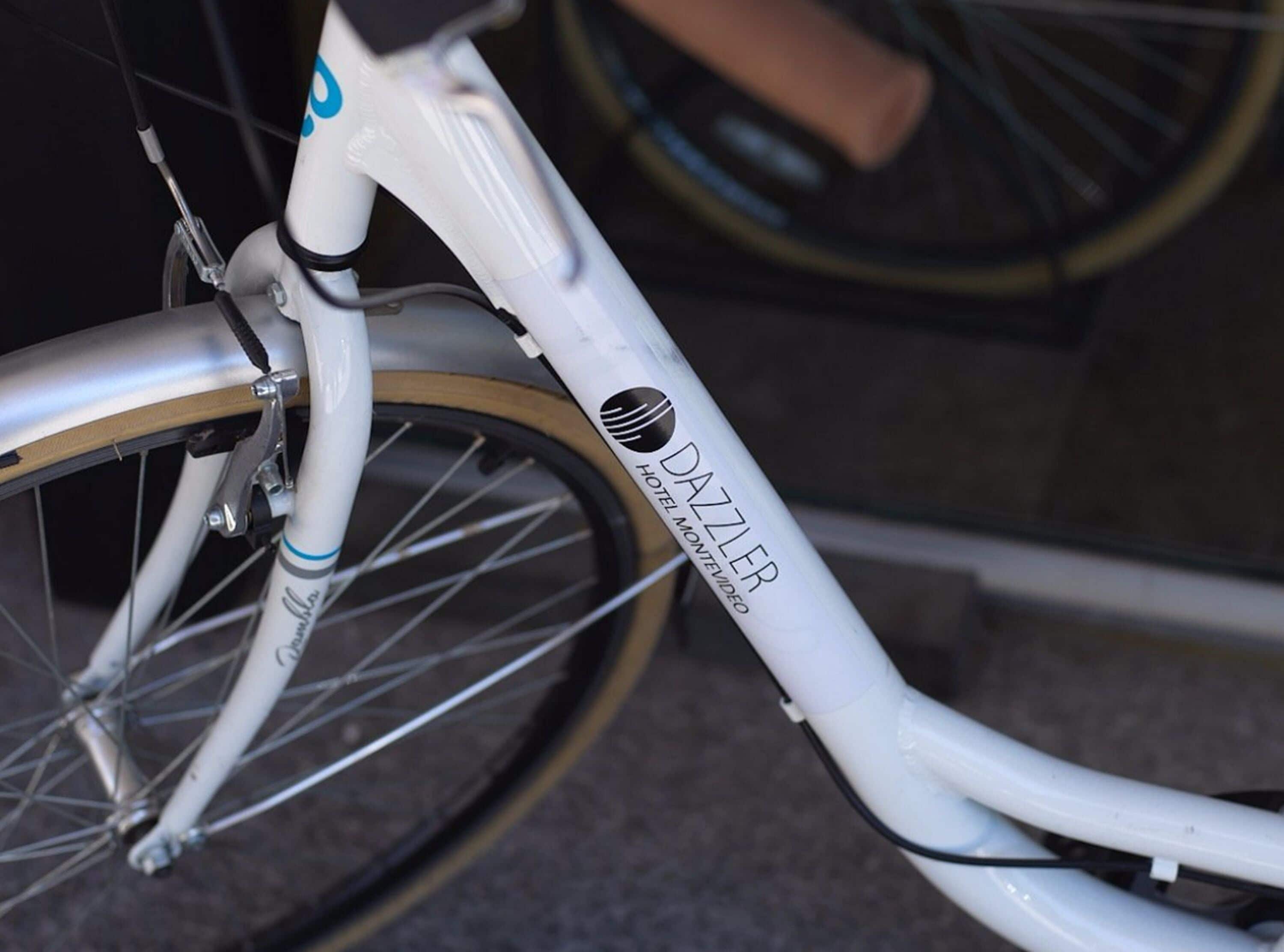A bicycle with a white frame and a logo that reads "DAZZLER HOTEL MONTEVIDEO."