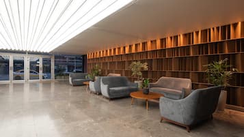 Un moderno vestíbulo con asientos, entrada de vidrio y pared de madera con estantes.