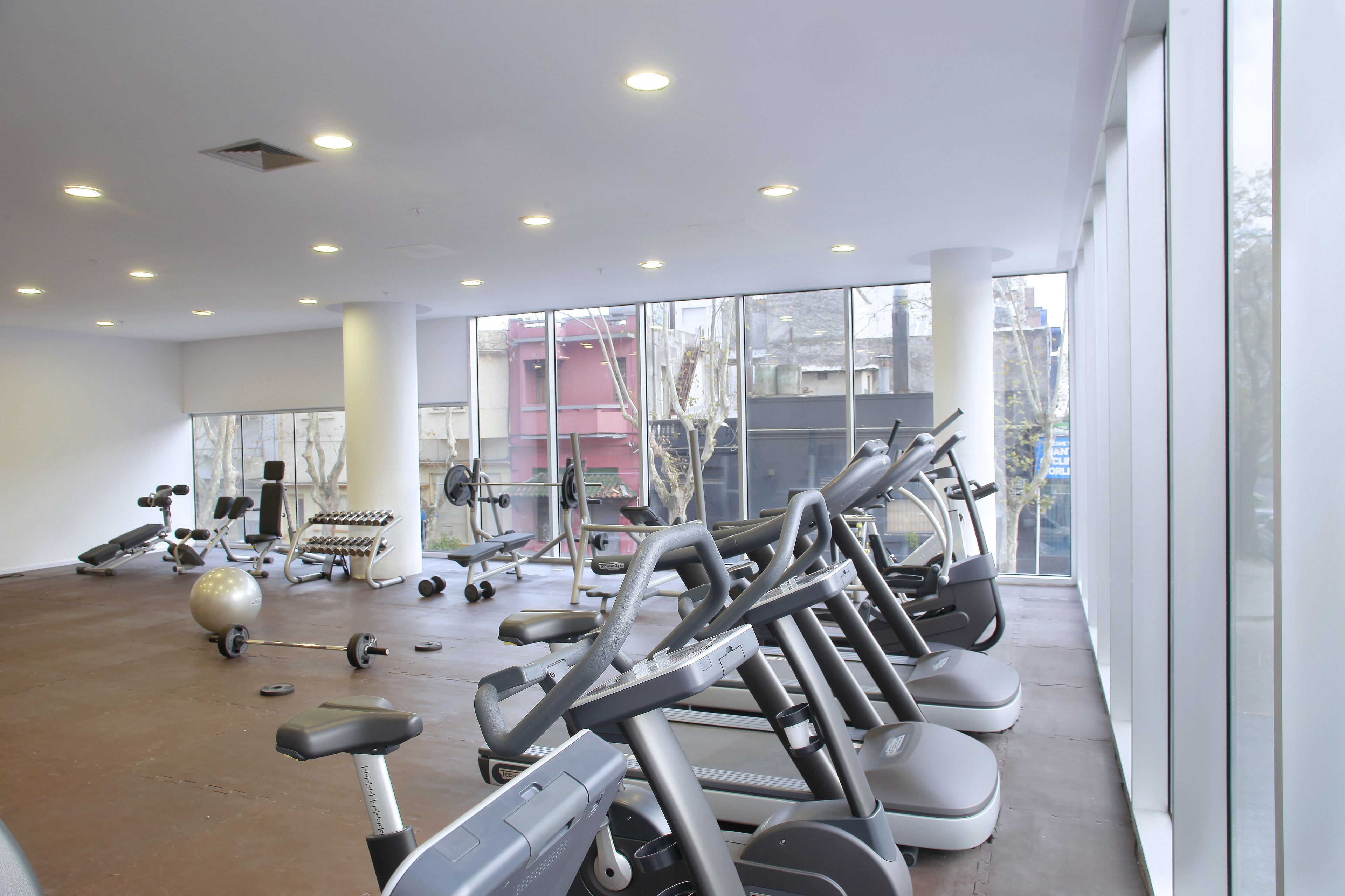 A gym with exercise equipment, large windows, and a concrete floor.