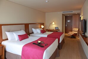 A hotel room with two beds, a desk with a lamp, a chair, and a television. - Dazzler by Wyndham Montevideo (Montevideo)