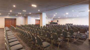 Un salón de conferencias con filas de sillas, un atril y una pared con el texto "DAZZLER".