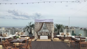 Een dakterras met een houten terras, zitplaatsen buiten, een overkapping en uitzicht op de skyline.