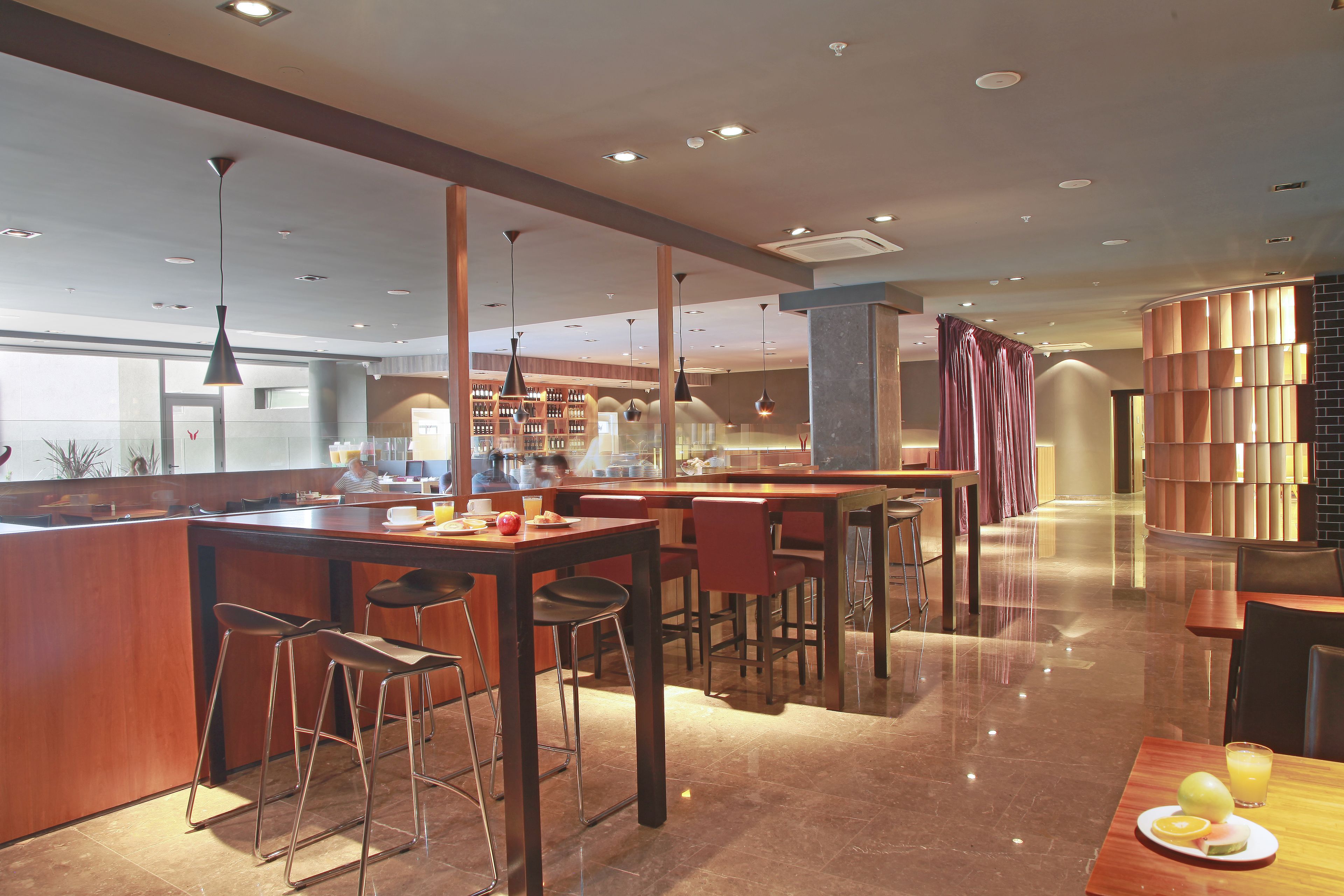 A modern restaurant with a bar area, high ceilings, and contemporary lighting.