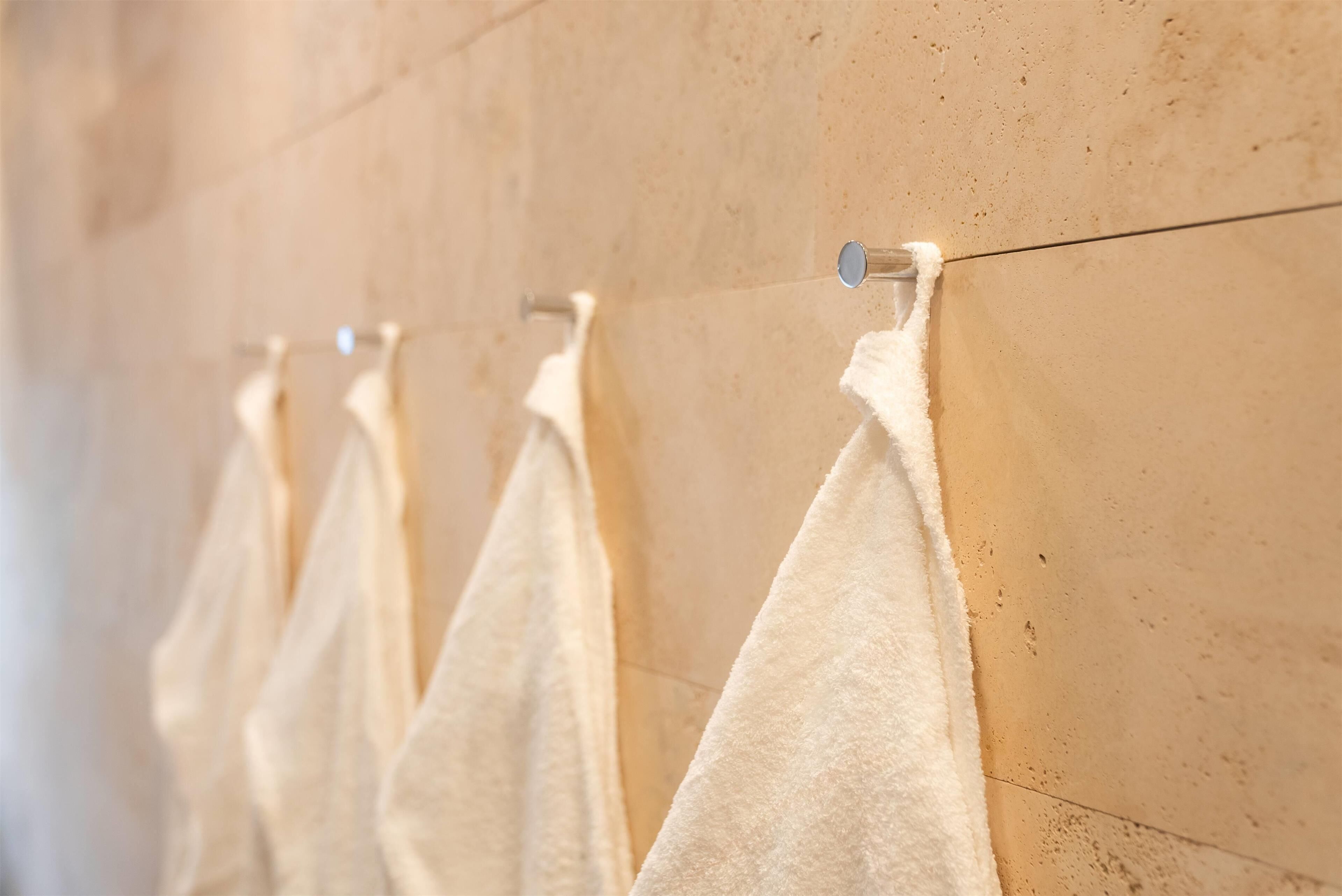 Een rij witte handdoeken hangt aan een wandrek in een badkamer.