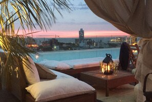 Terraza en la azotea con piscina, zona de estar y vista al horizonte de la ciudad.