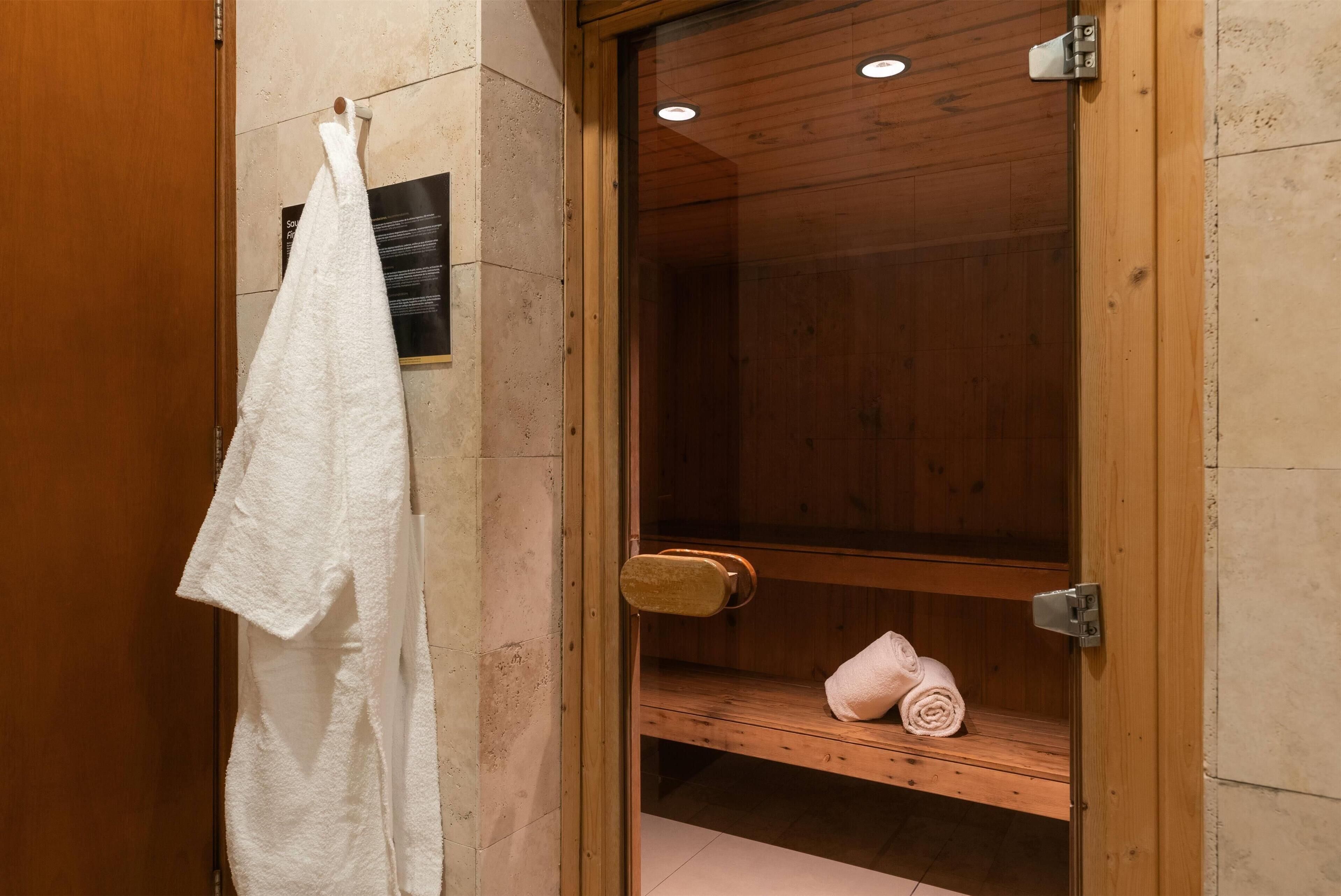 Una sauna de madera con un banco y un perchero con una toalla colgada.