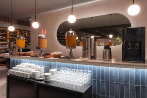 A modern bar area with a beverage station, a coffee machine, and a water dispenser. - Dazzler by Wyndham Montevideo (Montevideo)