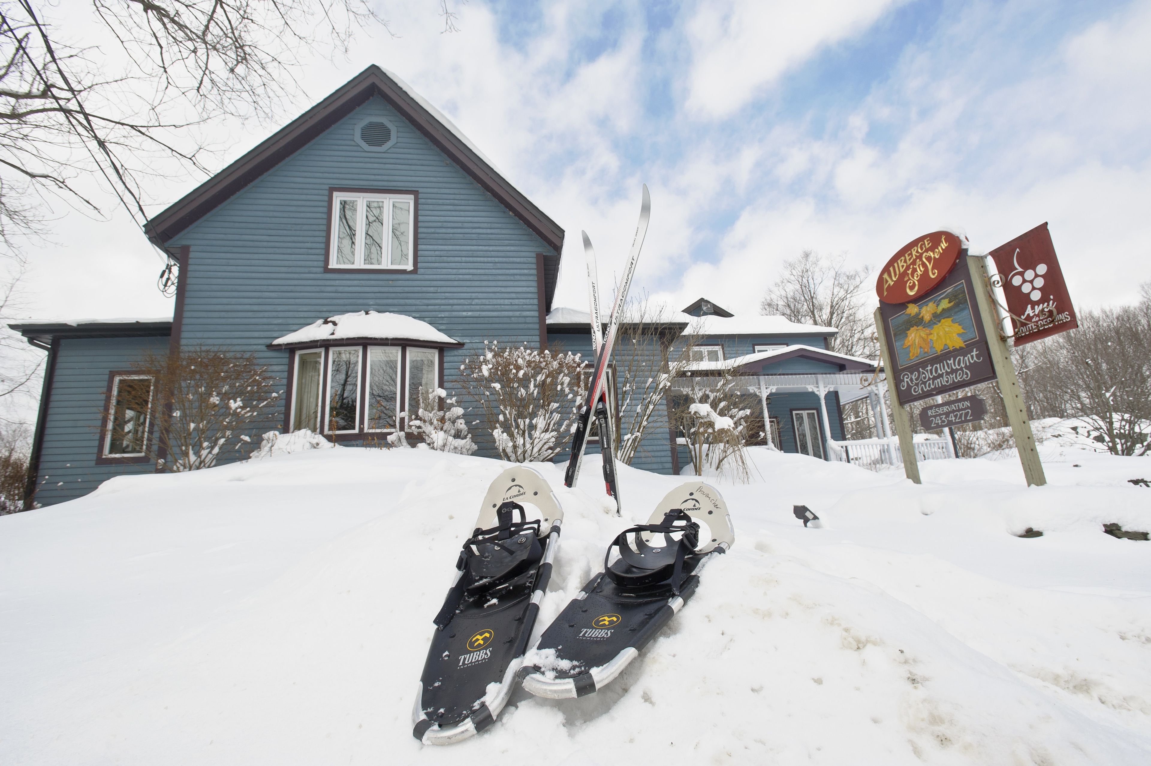 Ein schneebedecktes Haus mit einem Schild für ein Restaurant und einer Telefonnummer.