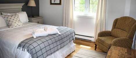 A neatly made bed with a plaid blanket, a bedside lamp, and a framed artwork on the wall.
