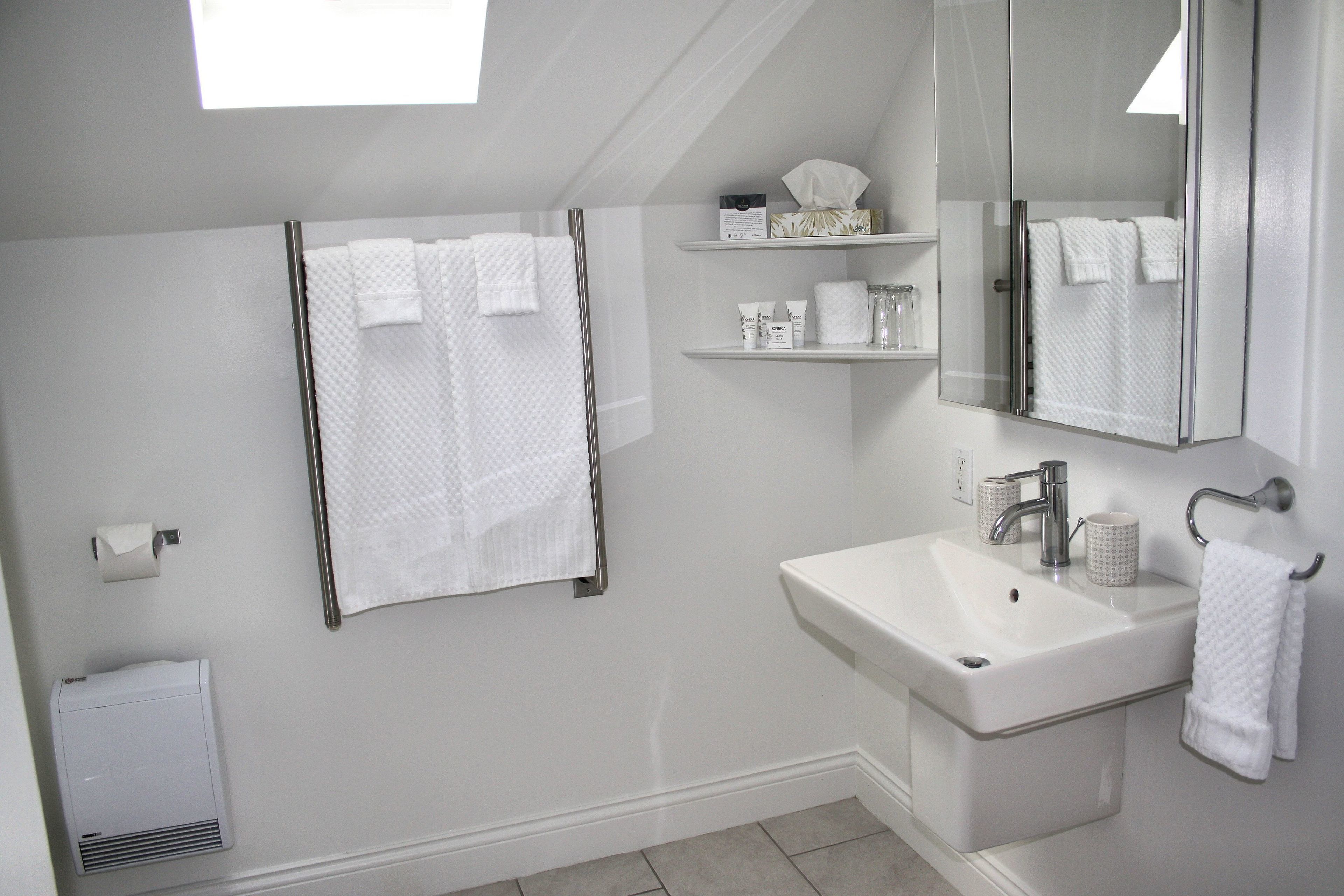 A bathroom with a white sink, a mirror, and two towel racks.