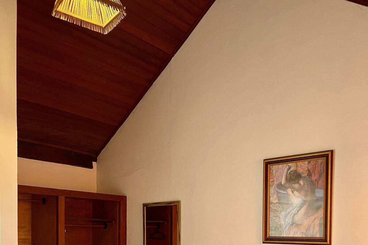Une chambre à coucher avec un lit en bois, un tableau au mur et une armoire.