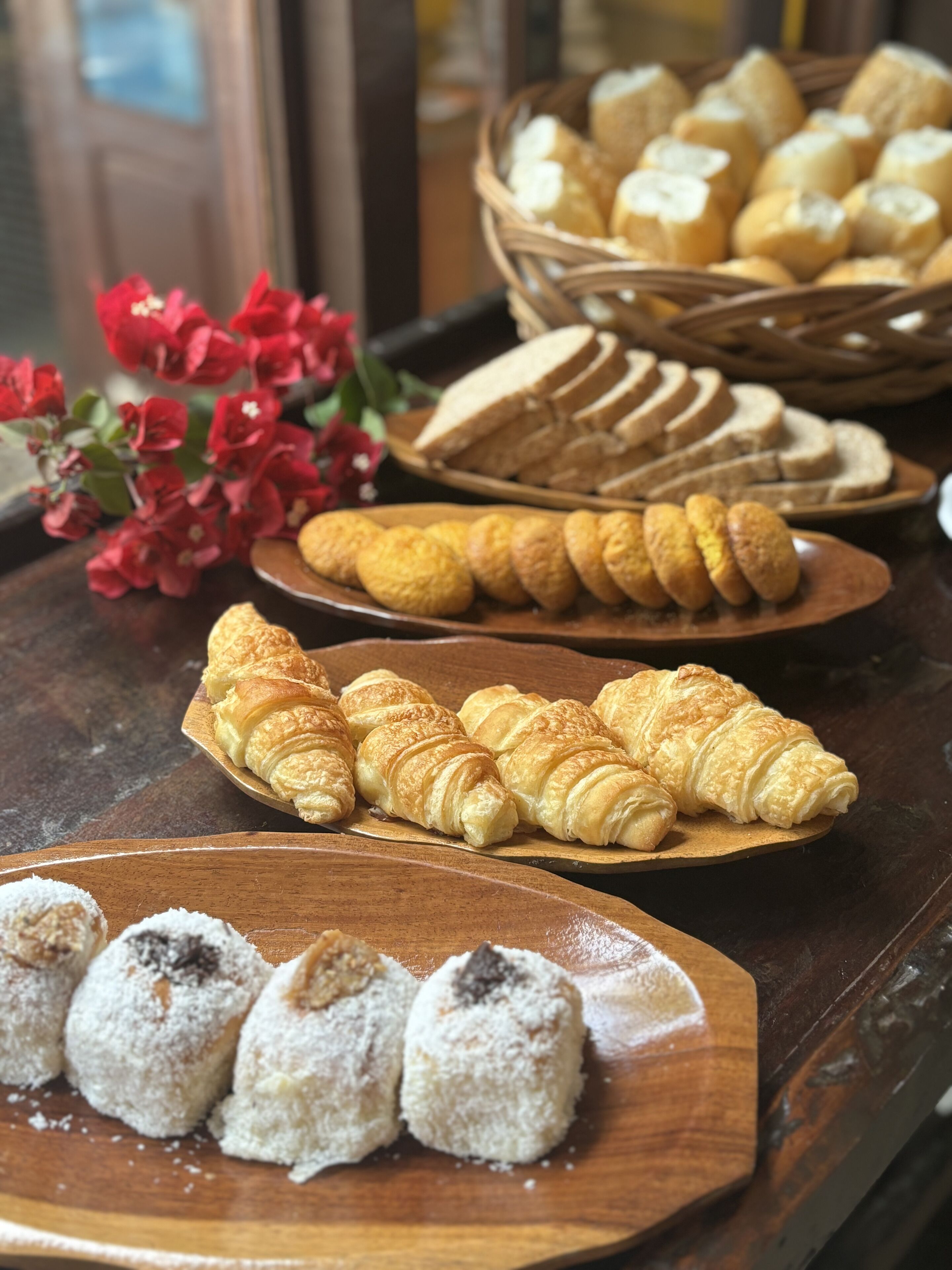A variety of pastries on wooden serving boards, including croissants and other baked goods.