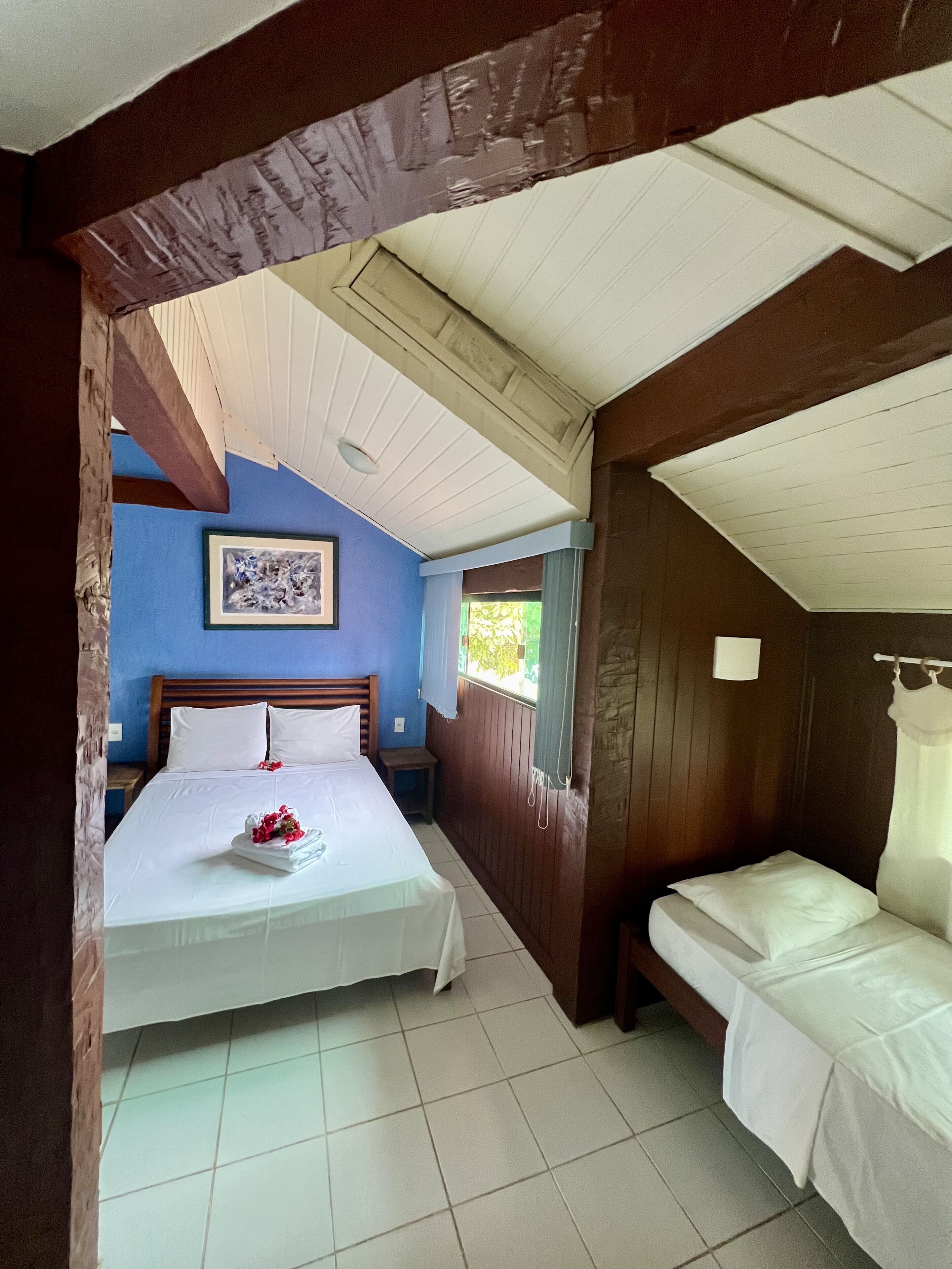 A bedroom with a large bed, a smaller bed, a nightstand, and a framed picture on the wall.