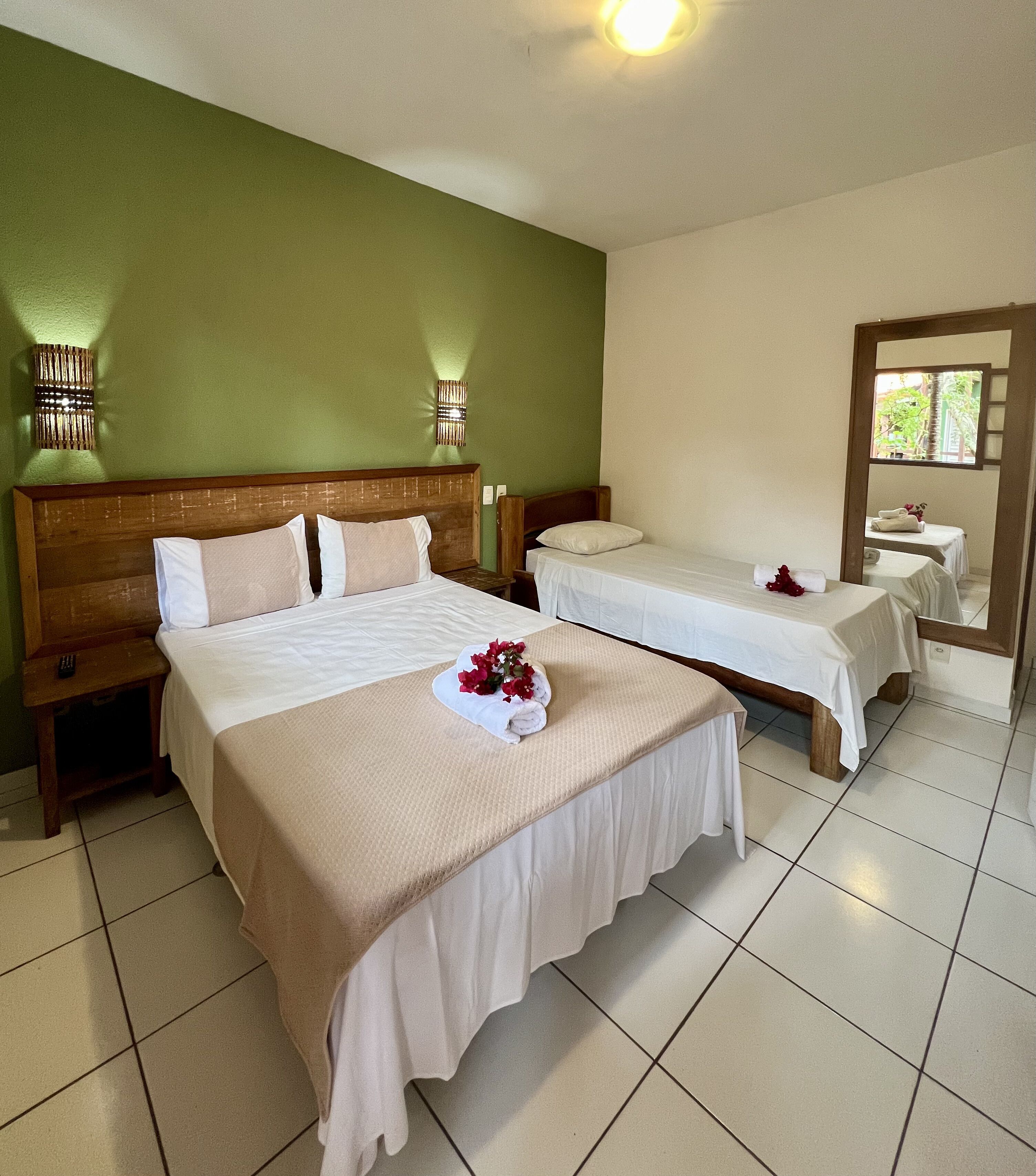 A hotel room with two beds, a green wall, and a large mirror.