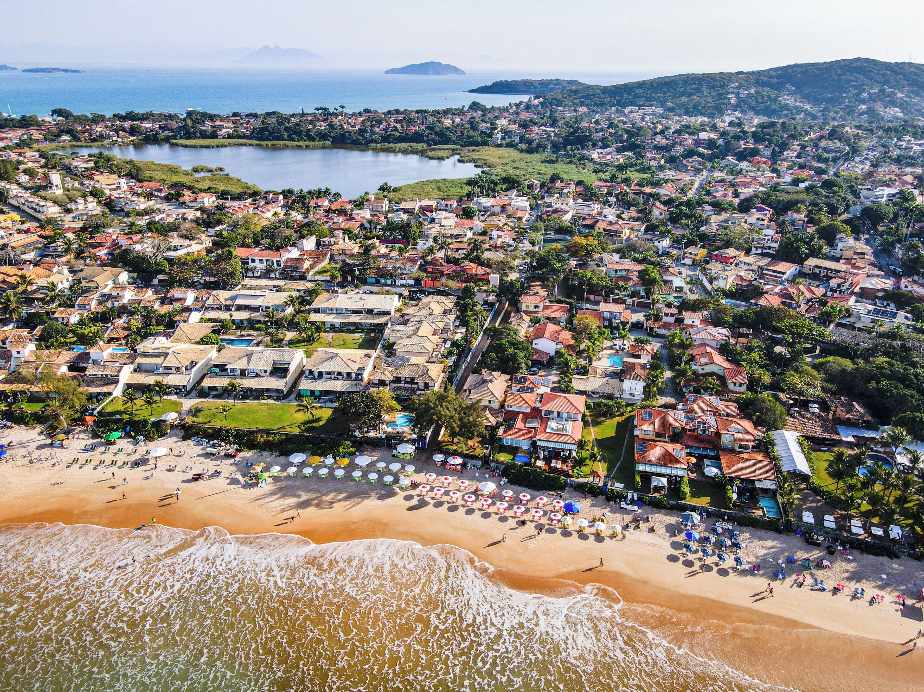 An aerial view of a coastal town with a beach, houses, and a lake.