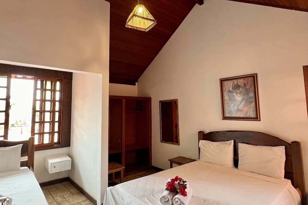 Une chambre d’hôtel avec un lit, une table de chevet, une fenêtre donnant sur un paysage agréable, un luminaire au plafond et un tableau au mur.