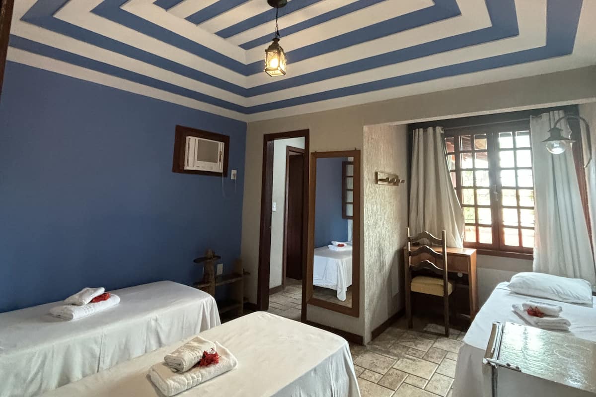 Une chambre d’hôtel avec deux lits, un bureau, une chaise et une fenêtre avec des rideaux.