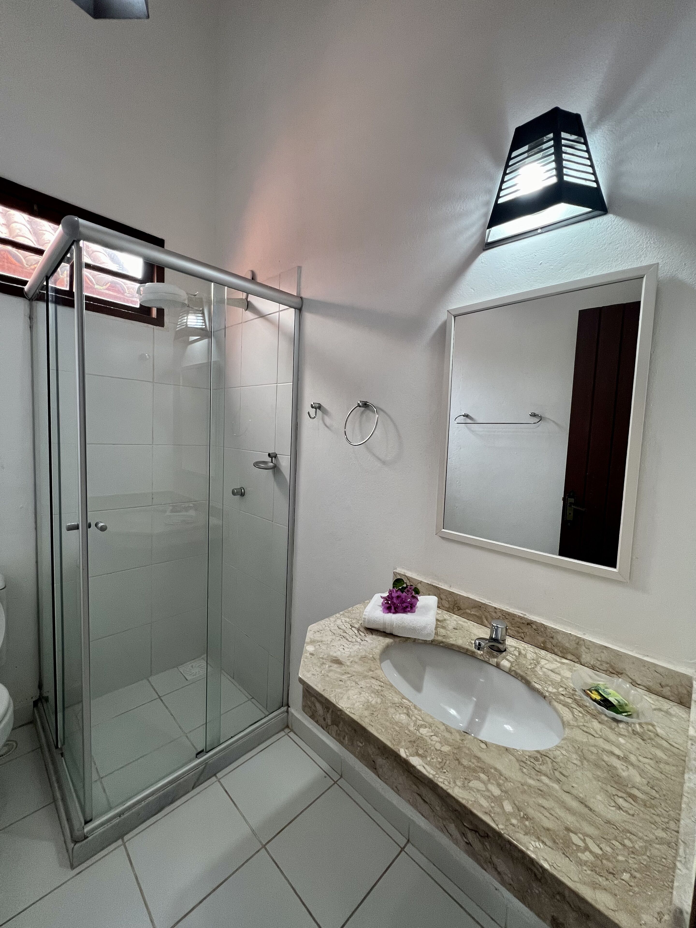 A modern bathroom with a glass shower enclosure, a marble sink, and a large mirror.