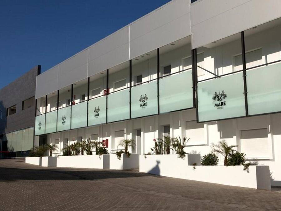 Un hotel moderno con fachada limpia y blanca y amplios ventanales de vidrio.